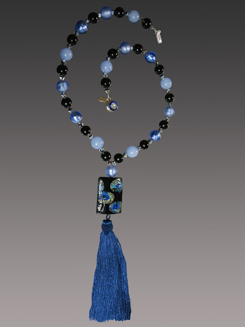 This stunning on trend necklace features a "Van Gogh" limited edition blue Starry Night Venetian glass rectangle with silk-knotted indigo,pale blue, and biack Venetian glass beads, a luxurious blue silk tassel, and a gold druzy sterling clasp.   Necklace 30" Silk Tassel 4-1/2"  ONLY THREE AVAILABLE


 

*This authentic lampwork Murano Glass Bead is one of a kind, big and bold made with amazing skill and time. Named "VanGogh" because the little paintings inside look like scenes from the paintings, they measure almost 2 inches in length, and the pattern is always different owing to the handwork. This particular bead features shades of black, luminous starry blue, and aqua. 