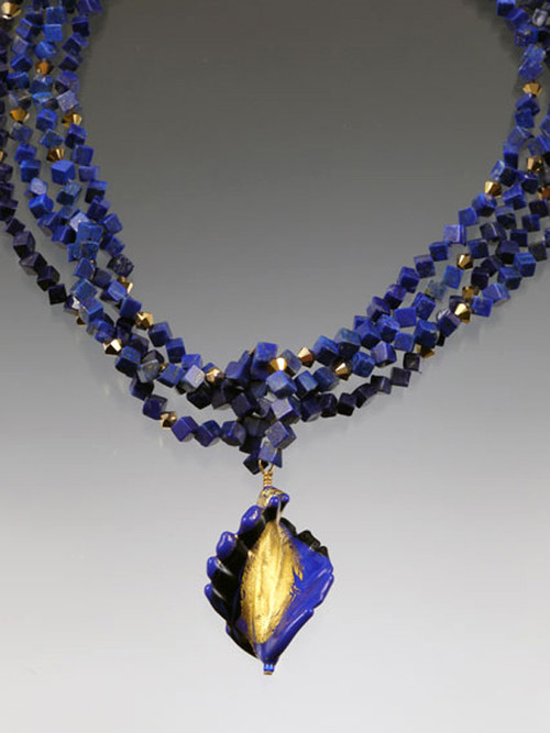 Luxuriate in six strands of Grade AAA lapis dice spaced with 24K Swarovski crystals.  A dramatic Venetian glass swirl centerpiece creates an elegant torsade look. 
