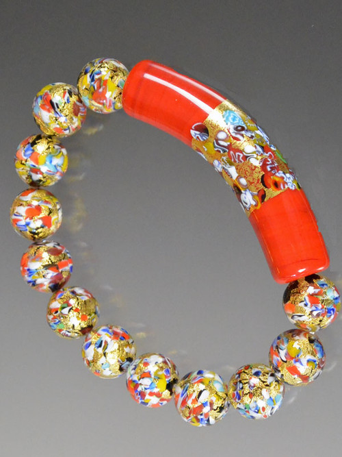 Make a dramatic statement with one fabulous bracelet or stack it with others in complementary colors. This Klimt stretch bracelet features a limited edition 60 mm curved tube (named after the mosaic style renowned painter) with an exterior band of gold with small bits of mosaic (millefiori) embedded on a base of red Murano Glass.   Perfect for the holidays and everyday!  7-1/2-8"  VERY LIMITED