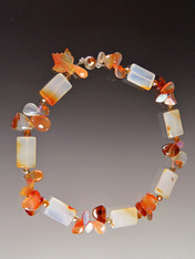 This delightful collar will lift your spirits and make you glow in the sunny weather.  It features unusually multi-toned carnelian rectangles spaced with precious clusters of glass carved leaves, tourmaline and fire agate, finished off with a complimentary Swarovski Crystal sterling clasp.  18".

