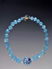 If you love aquamarine and want to make a statement, this is for you. Grade AAA rich blue grduated aquamarine faceted beads frame a beautiful Venetian Sasso window center with flashes of aqua, pink and black. A custom blue topaz clasp completes the picture. 18"