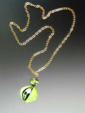 This dramatic necklace features a a 2-1/2" pendant glass beads on a 24K Ultraplate chain. The focal point is a 30 mm. peridot black Windows* blown Sasso Swirl topped with a 16mm matching lime round window where you can see an internal cylinder of 24K gold foil with an internal lime spiral and an end cap of deep dark chocolate. Chain is 24"