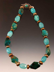 An intense showstopper to circle your neck and brighten any day.  Freeform chrysocolla faceted nuggets, luminous aqua calcedony faceted barrels, golden bronze freshwater pearl wheels with a dramatic center stone (no two alike). Chrysocolla or turquoise sterling clasp 18"