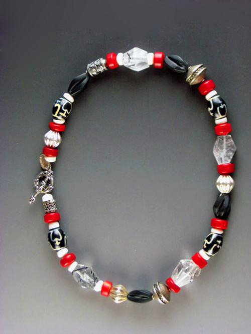 A spectacular collage featuring faceted Brazilian tourmalated quartz, red coral, vintage Bali silver beads, black onyx swirl beads, patterned African horn, and white shell.