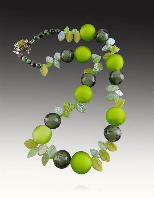 This striking collar by Yumiko Togashi features a collage of green and lime shiny and matte Venetian glass beads paired with delicate hand carved glass iridescent leaves, ruby zoisite beads and a vintage gaspeite silver clasp.  Light and elegant for any occasion. 18"