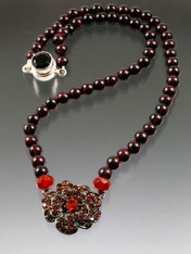 Many years ago I discovered a vintage French flower necklace with tiny crystals set in black metal.  I took it apart and used each precious flower as the centerpiece for a limited edition necklace.  This design features grade AAA silk hand-knotted garnet with carnelian rondels and a carnelian toned deco flower.  18"  