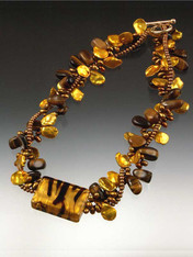 Be queen of the jungle with this dramatic, dimensional torsade featuring tiger eye, grade AAA gold and bronze petal pearls, and a magnificent 14K Venetian glass striped tiger highlight.  14K toggle clasp.  20"