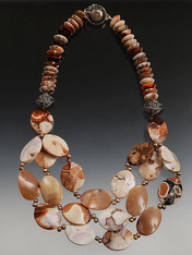 3-strand bib of "conglomerate"* jasper features unusual patterns of peach, pink, bronze, cream, chocolate brown and sienna. Mocha jasper scalloped waves and pleated conglomerate ovals hang from a chain of Indonesian silver and jasper wheels with a mabe pearl sterling clasp.  This statement piece is the only thing you'll need to wear with any color in your wardrobe. Longest strand 21" ONLY TWO!!
