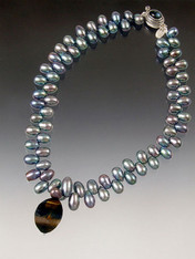 A rare blue tiger eye swirl suspended on a strand of luminous large peacock blue "firecracker" pearls. 17-1/2"