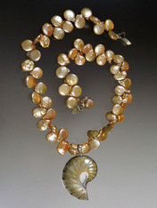 A luminous natural outlined nautilus shell anchors a strand of grade AAA champagne peach coin pearls.  Absolutely stunning.  18"  Nautilus Shell 2"
