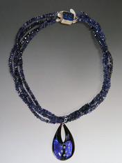 Blue is a big color trend this season and this dazzling necklace has it all - three strands of grade AAA Iolite (a member of the sapphire family) rondels with a custom sterling iolite clasp and a one of a kind authentic Venetian glass pendant in the shape of a teardrop featuring sterling silver over deep blue Murano Glass with sparkling cubic zirconia near the surface.  The entire teardrop is encased in clear Murano Glass giving it a magnified effect. Totally stunning in person with great depth and flashes of color. 22" Pendant 1-1/2" 
