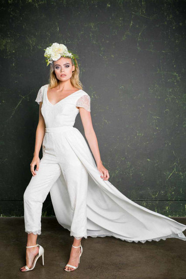 The Lowry epitomises the modern day bride. This design has a classic and flattering cigarette cut trouser leg. This beautiful bridal jumpsuit is made entirely of lace which comes all the way from Australia and boasts a contemporary, fan design while giving a pretty, vintage vibe. The capped sleeves and trouser hem are both finished with a scalloped edge.